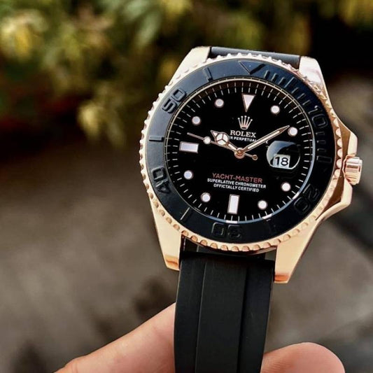 Luxury watch with black dial and rose gold accents held by a hand against a blurred natural background