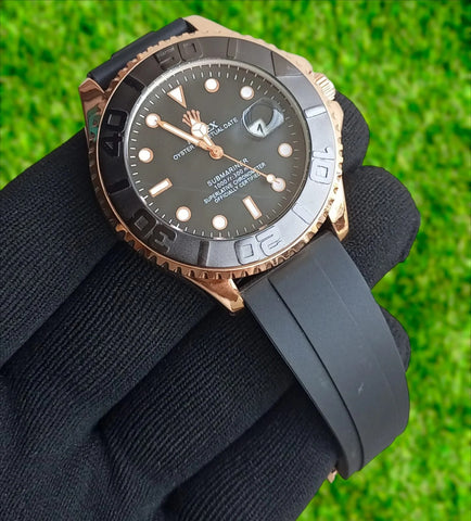 Luxury watch with black strap held by a gloved hand against a grass background